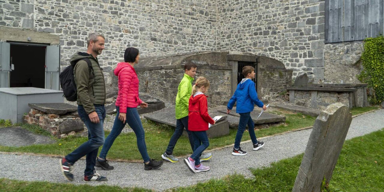 family of 5 walking beside stone building 